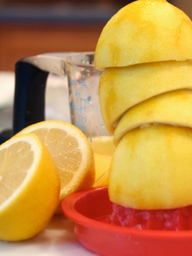 A number of lemons are cut in half and juiced.