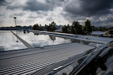A rooftop filled with solar panels, above is a cloudy grey sky