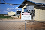 A keep out sign and barb wire fence surrounds a geothermal power plant