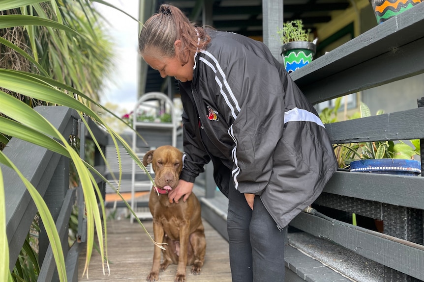 Kellie with her dog on the steps up to her home.