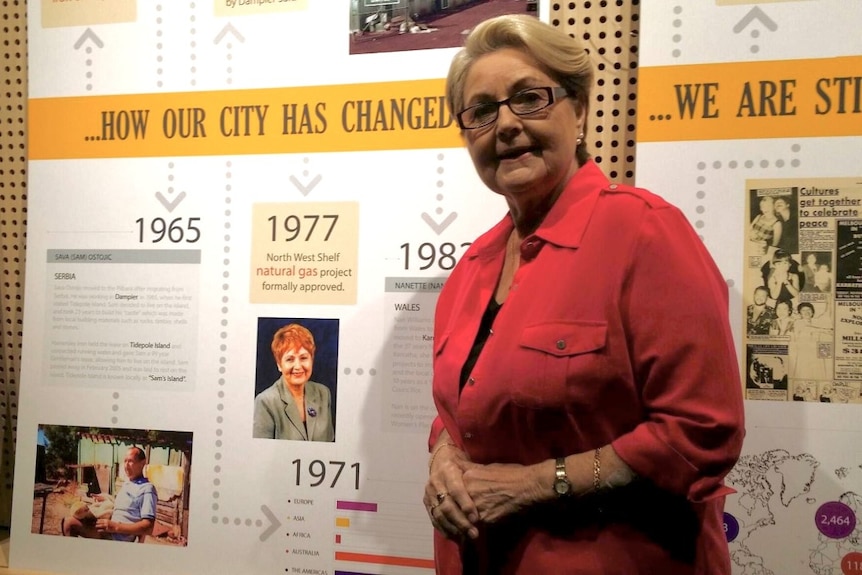 A woman standing in front of an interpretive board.