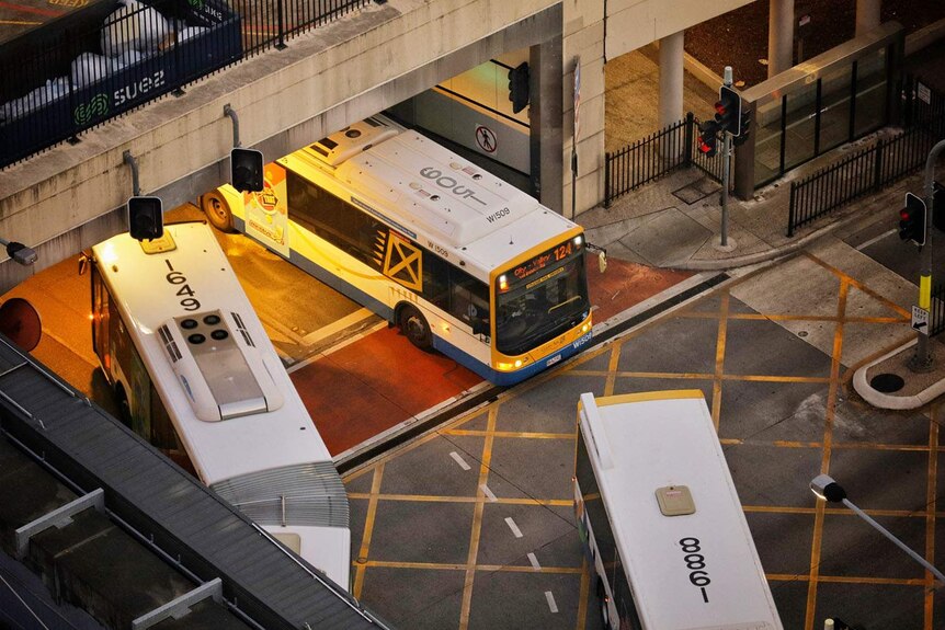 Looking down at buses going into the busway tunnel at the traffic light intersection at Melbourne Street at South Brisbane.