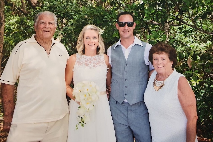 A couple at their wedding, surrounded by an aunt and uncle on either side