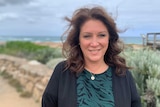 A middle-aged woman looking past the camera with a beach in the background