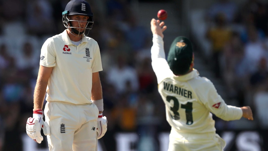 Joe Root looks frustrated. Out of focus, David Warner hurls the ball into the air in celebration.