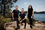 Colour photograph of Kevin O'Brien, Daniel Browning and Karen Norris posing on sandstone in front of Barangaroo Reserve