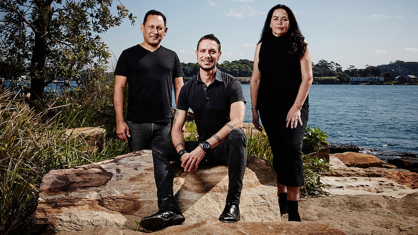 Colour photograph of Kevin O'Brien, Daniel Browning and Karen Norris posing on sandstone in front of Barangaroo Reserve