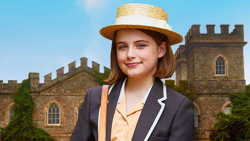 A young girl dressed in school uniform in front of an impressive brick school