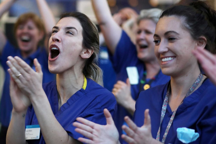 Health workers in medical scrubs smile and cheer