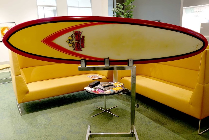 A red yellow and black surfboard on a stand