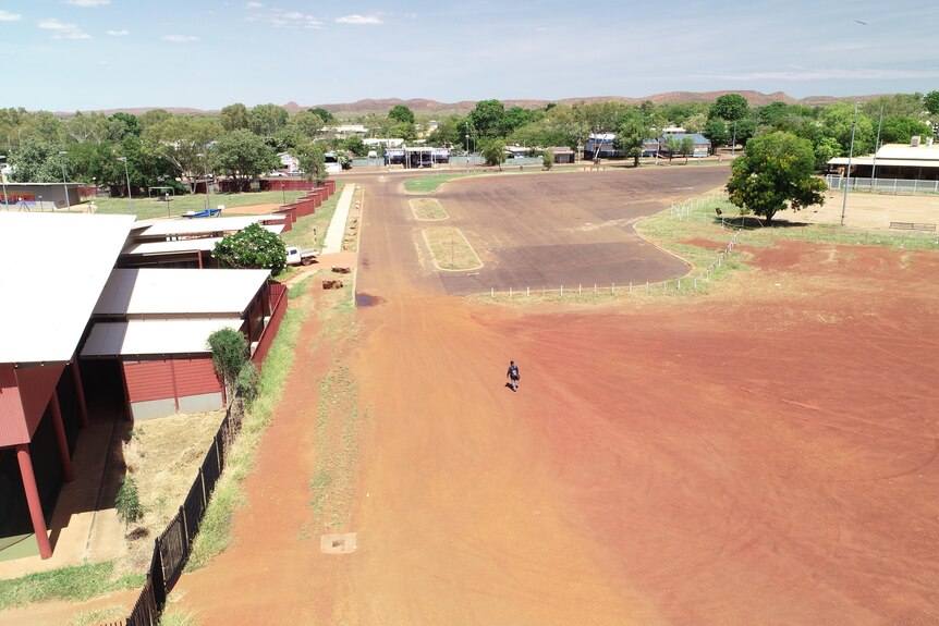 An aerial shot of Anthony Johnson walking along a red dirt street.
