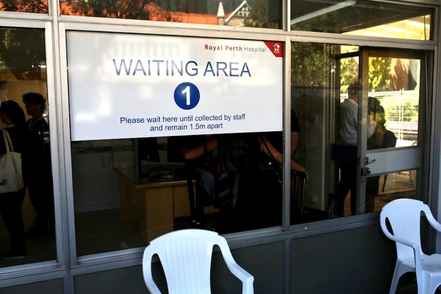 A sign says "waiting area 1" in front of some white plastic chairs.