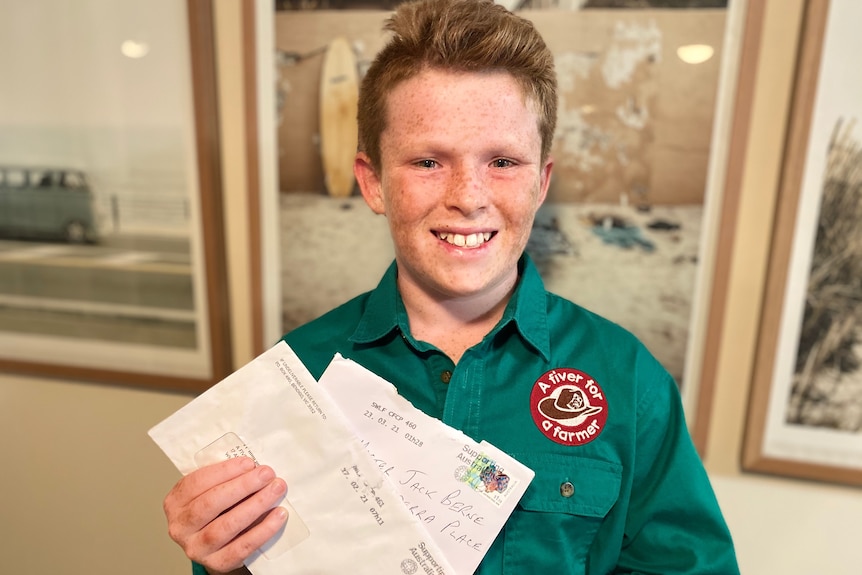 A 12-year-old boy holding some letters.