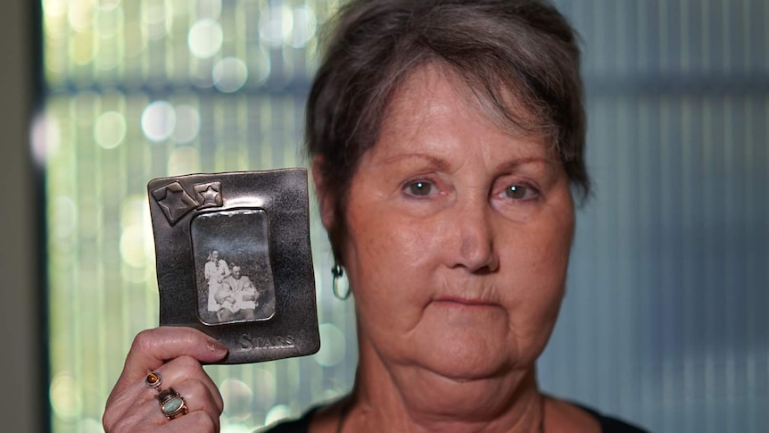 A portrait of a woman holding a photo of her family