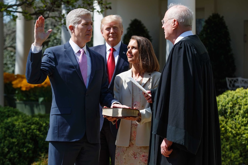 Judge Neil Gorsuch raises his right arm as a re-enactment of the judicial oath is carried out.