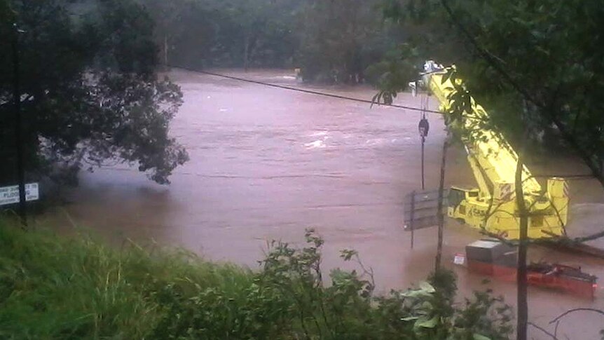 The flooded Bloomfield River covers a bridge in the Daintree in far north Queensland