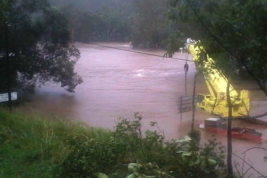 The flooded Bloomfield River covers a bridge in the Daintree in far north Queensland