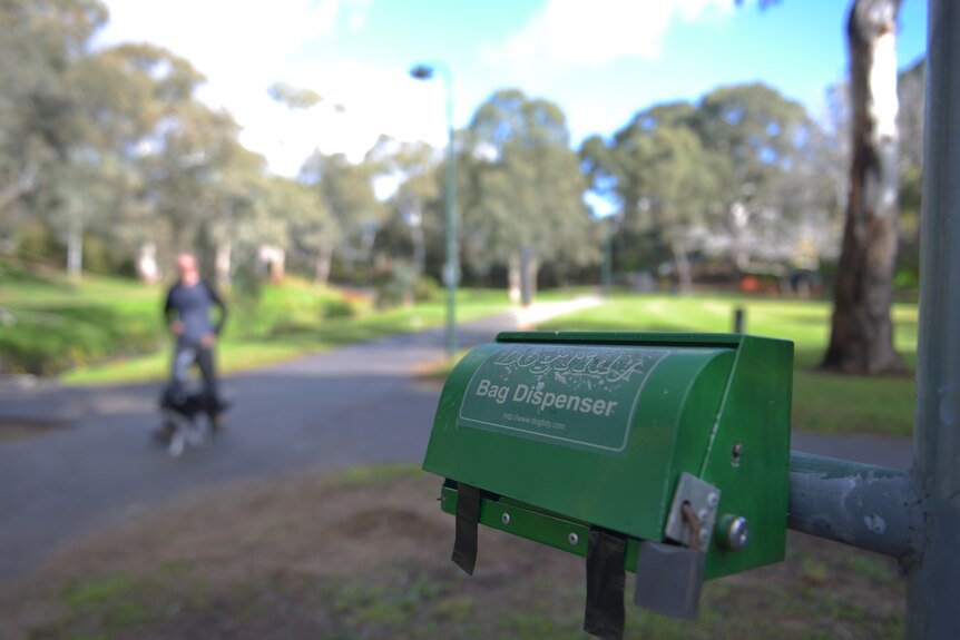 A dog poo bag dispenser in a park.