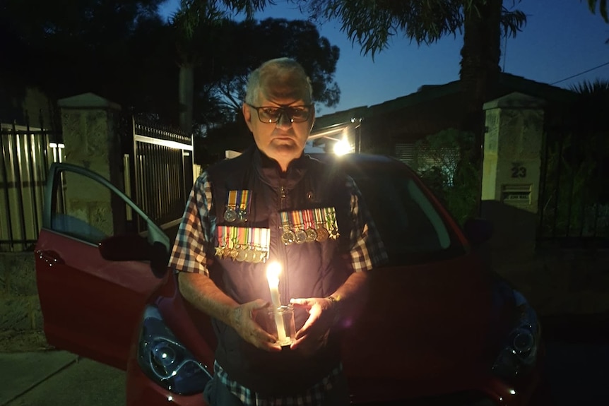 Terry Walsh stands in his driveway holding a candle.
