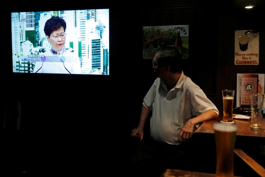 A man watches Carrie Lam on TV.