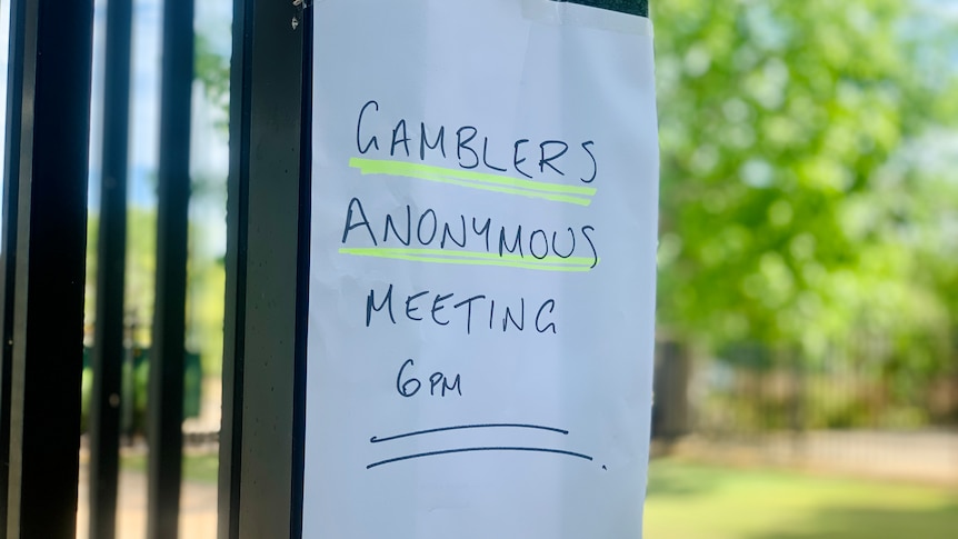 A white poster stuck on a fence advertising a gamblers anonymous meeting