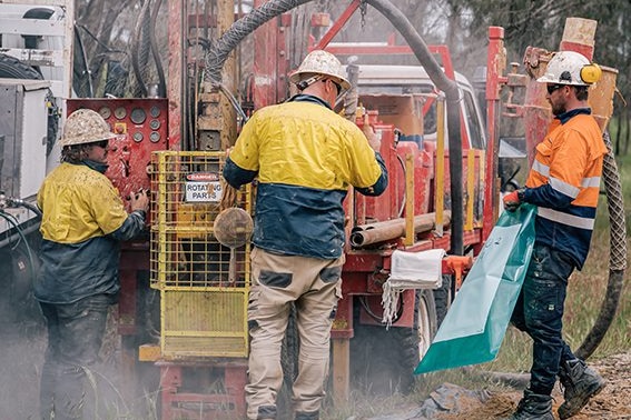 Three men operating a rig that's drilling into the ground