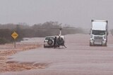 A helicopter lands near an SUV inundated by floodwater.