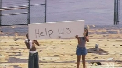 Survivors in New Orleans hold up a sign asking for help.