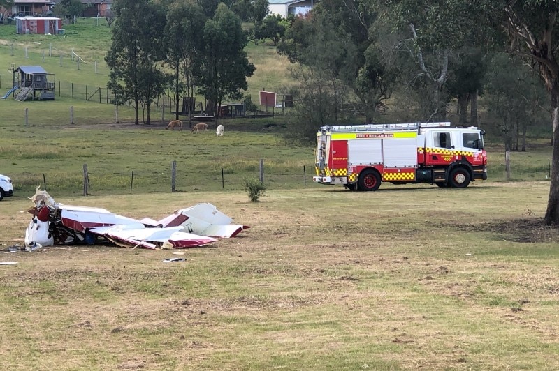 a crashed plane and a fire truck in a country backyard