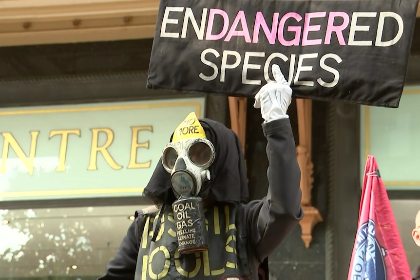 A person in a mask holding a sign