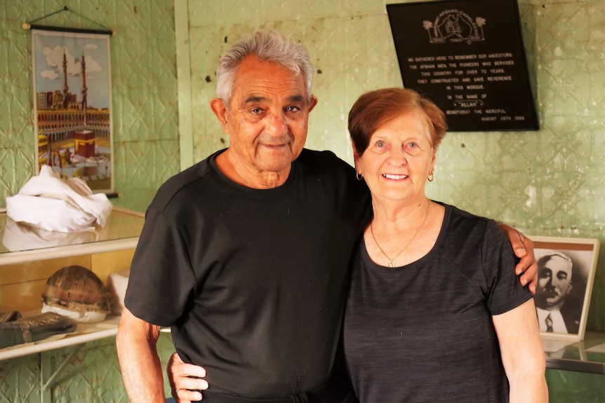 A couple smiling and standing together inside a mosque.