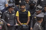 A suspect of the Bangkok blast walks with police officers