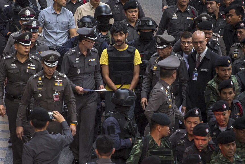 A suspect of the Bangkok blast walks with police officers