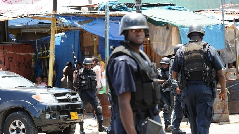 Under attack: Police patrol Kingston's streets amid spreading unrest.