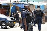 Under attack: Police patrol Kingston's streets amid spreading unrest.
