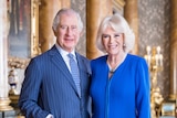 A portrait of Charles and Camilla standing together dressed in blue.