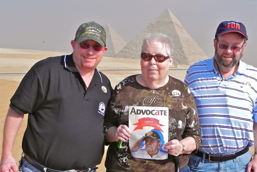 Three people stand in front of the pyramids in Egypt.