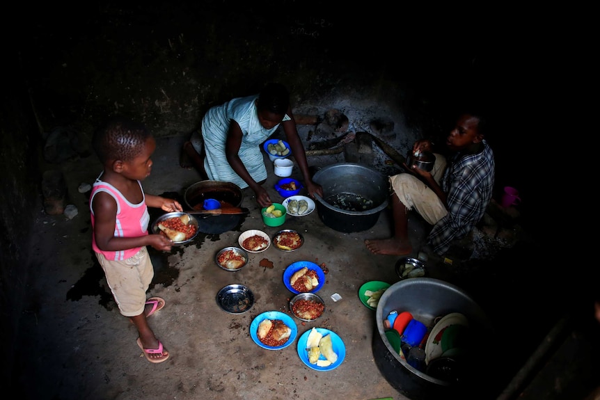 Several plates loaded with beans and bread are served up and carried by children.
