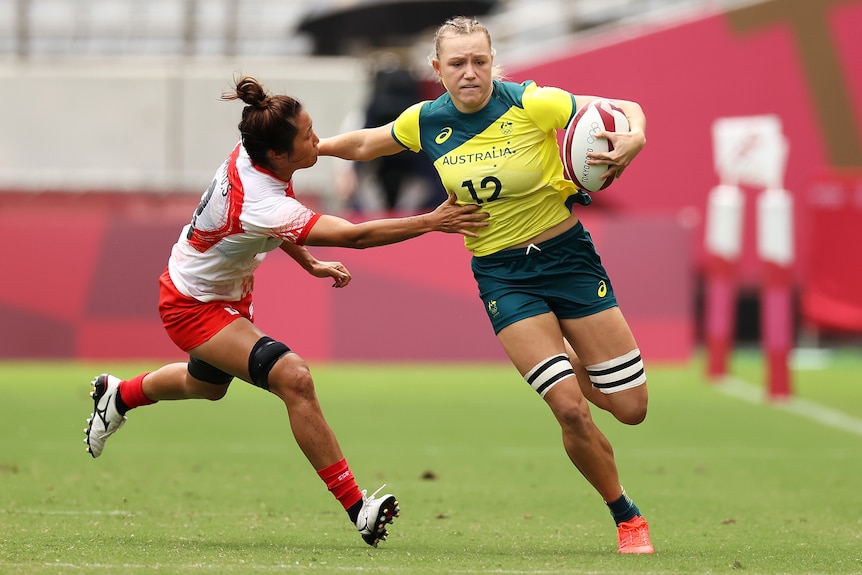 Australia's Maddison Levi storms past a Japanese opponent in rugby sevens at the Tokyo Olympics