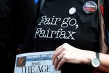Staff on strike wears shirt saying "Fair go, Fairfax" while holding a copy of The Age newspaper.