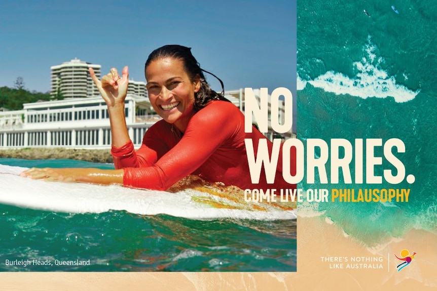 A woman on a surfboard displays the hang ten sign in the new Tourism Australia ad campaign