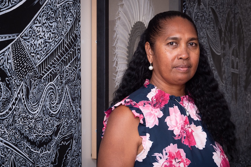 Torres Strait Islander woman in front of Indigenous and Dhari artwork