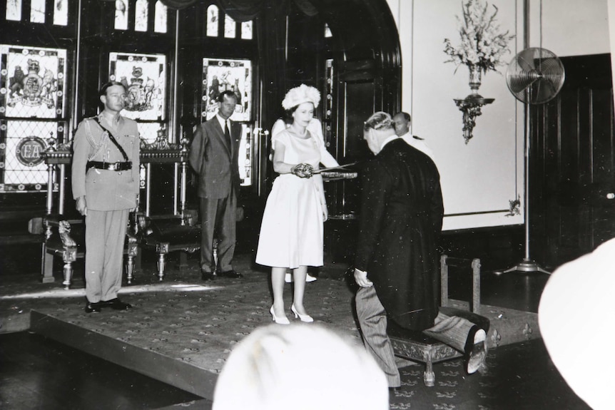 Sir James Holden kneels for his knighthood.