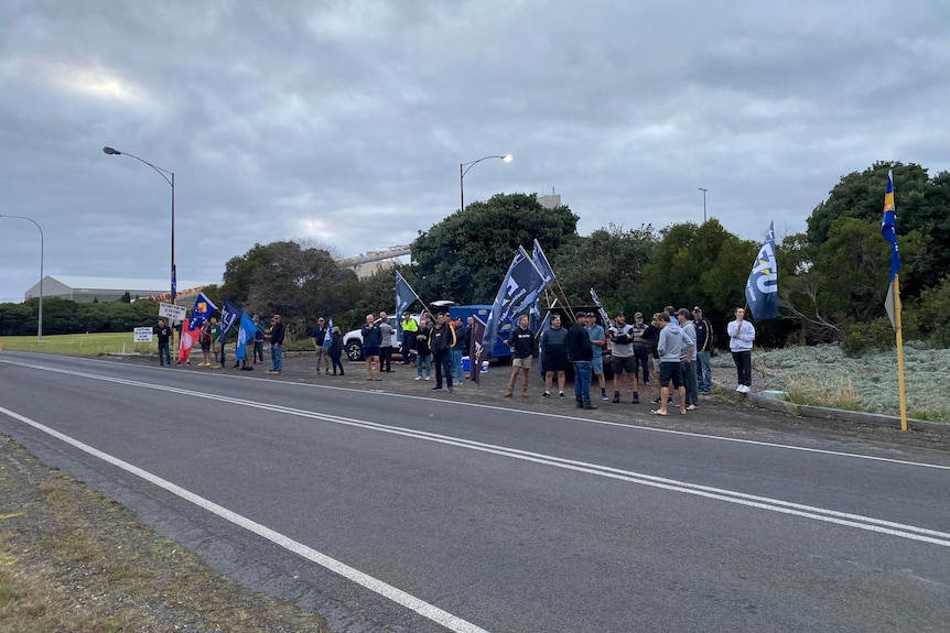 A group of striking workers outside an industrial site.