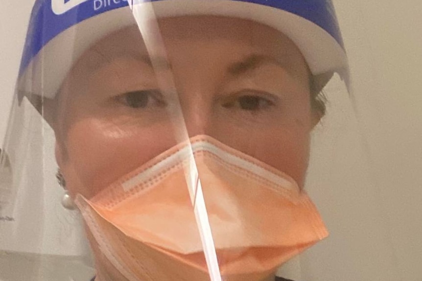 Lesley wears full PPE, including a face mask, face shield and hospital gown