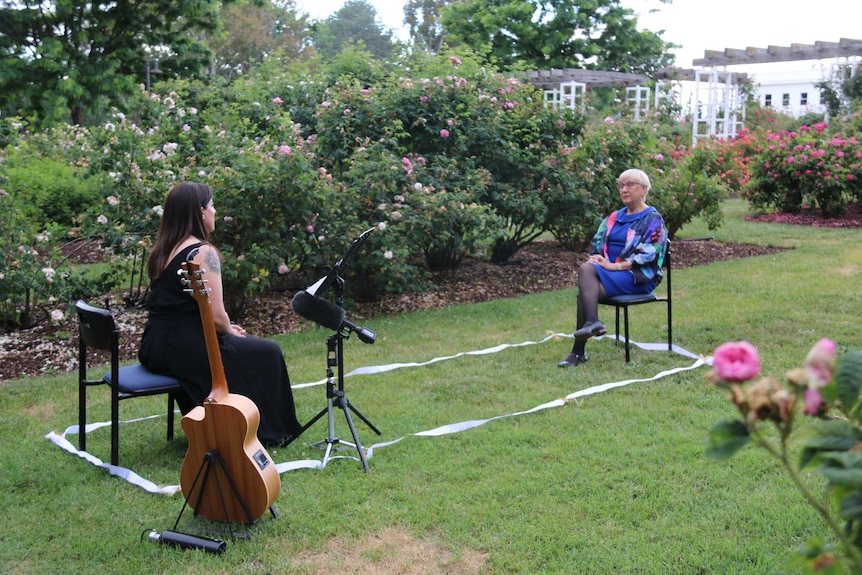 Rachael sits and sings, Robyn sitting about two metres away listening.