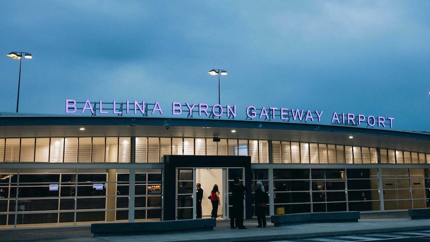 Ballina Byron Gateway airport entrance on dusk. Lights inside the airport terminal are on and the name of the airport is lit up 