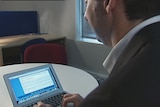 An unidentified man is pictured in front of a computer.