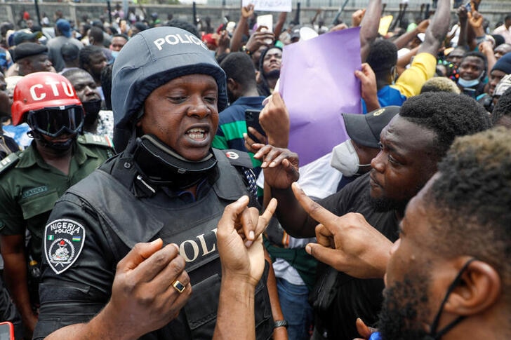 Demonstrators talk to a police officer during a protest over alleged police brutality, in Lagos.