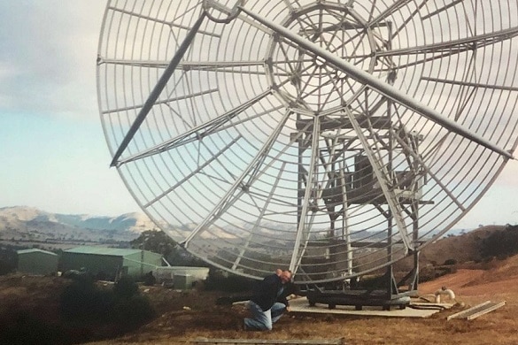 A man works on a large antenna in a paddock in Birchip, Victoria
